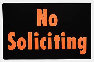 No soliciting sign with orange text against black.