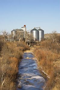Storage silos by creek in rural setting.