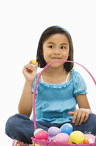 Girl sitting on floor with Easter basket full of eggs smiling