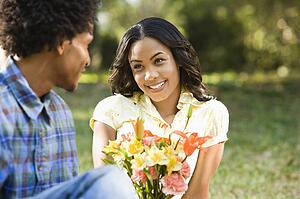 Man giving smiling woman bouquet of flowers.