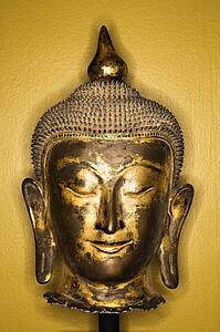 Bronze Buddha head from Thailand against yellow wall