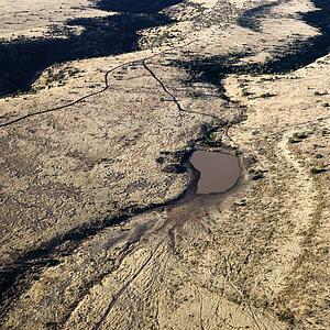 Aerial view of Arizona desert landscape with small water source.