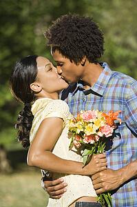Woman and man embracing and kissing in park.