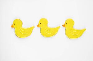 Three sugar cookies in shape of ducks with decorative icing.