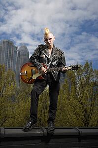 Male punk holding guitar with skyline 