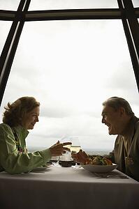 Caucasian mature couple at nice restaurant drinking wine and talking and laughing.