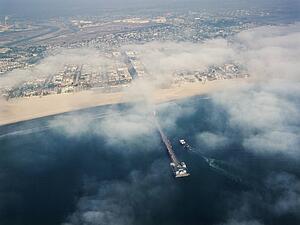 Aerial view of clouds covering beachfront and fishing pier in southern California