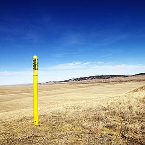Yellow petroleum warning pole in scenic landscape.