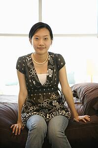 Female sitting on bed.