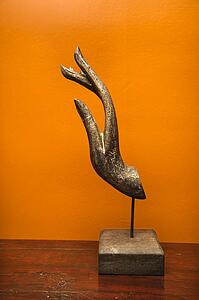 Carved hand sculpture from Thailand against orange wall.