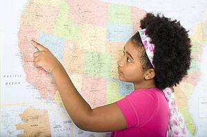 African American girl pointing on map of United States.