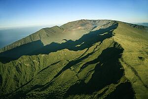 Aerial view of green mountain with Pacific ocean in background in Maui, Hawaii