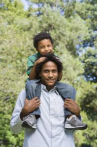 Father carrying son on shoulders in park