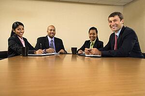 Businesspeople sitting at conference table smiling