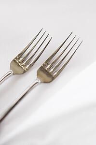 Sald fork and dinner fork on white table cloth.