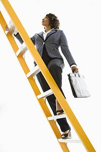 Businesswoman holding briefcase climbing ladder
