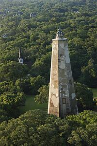 Aerial view of Old Baldy lighthouse in wooded park at Bald Head Island, North Carolina.