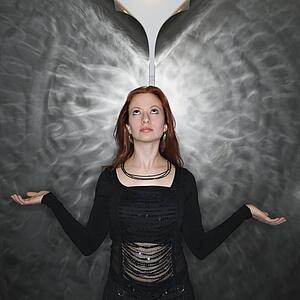 Woman in meditation pose looking up at parted metal background