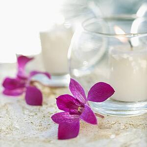 Close up of candles and purple orchids.