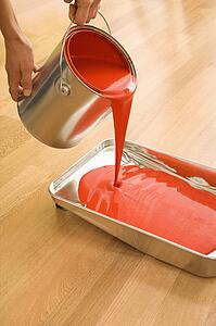 Pouring red paint from can into tray