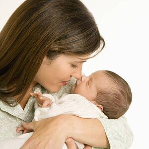 Mother nuzzling sleeping baby with nose and smiling