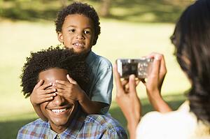 Woman photographing son in park with digital camera