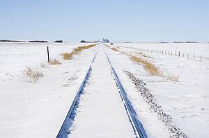 Railroad tracks in snow covered rural landscape