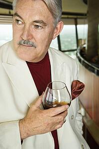 Man in suit holding snifter of brandy