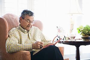 Man sitting in chair reading a book