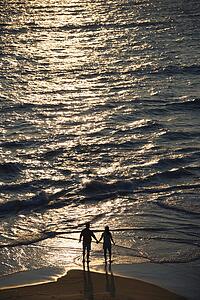 Aerial view of couple holding hands on beach in Bald Head Island, North Carolina at sunset