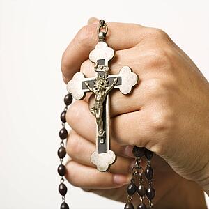 Woman's hands holding rosary with crucifix