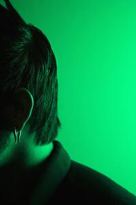 Close up side view portrait of attractive Asian Filipino young adult man tinted green.