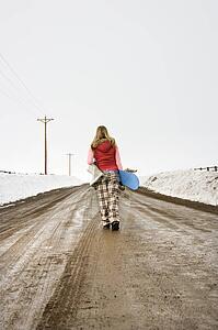 Walking carrying snowboard and boots
