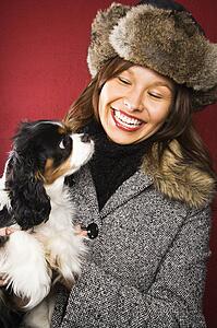 Woman wearing fur hat holding King Charles Spaniel