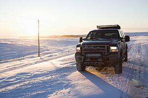 Truck on ice covered road and snowy rural landscape