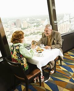 Senior couple having dinner in nice restaurant as man gives gift to woman