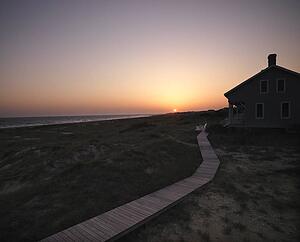 Sunset over coastal beach house with wooden boardwalk at Bald Head Island, North Carolina.