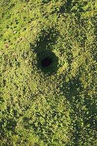Aerial view of collapsed lava tube surrounded by green trees in Maui, Hawaii