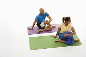 Man and woman sitting stretching on exercise mats
