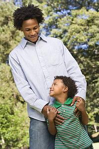 Father with hands on son's shoulders as boy looks up at him