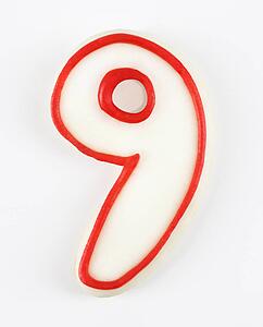 Sugar cookie in the shape of a number nine outlined in red icing.