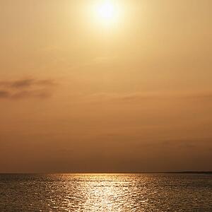 Sun over ocean with warm red tones