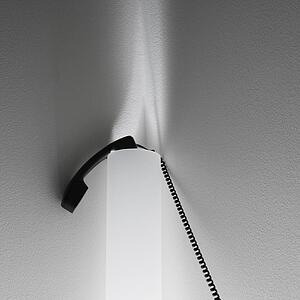 Receiver of corded telephone resting on sconce lighting on wall.