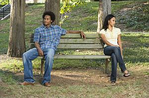 Sitting on opposite sides of park bench 