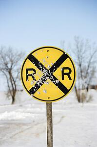 Railroad crossing sign in snow covered rural landscape.