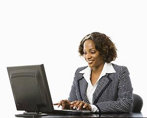 Smiling businesswoman sitting at desk typing on computer