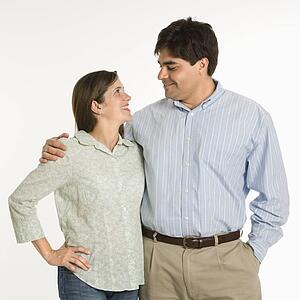 Couple standing smiling at each other against white background
