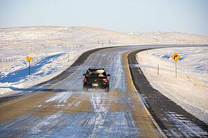 SUV on icy road in snowy landscape