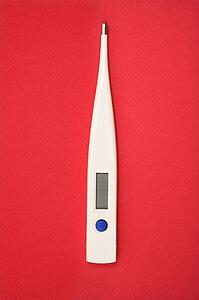 Digital thermometer on red background.