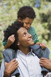 Father carrying son on shoulders in park
